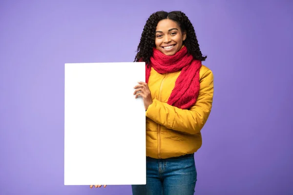 Preto menina segurando em branco pôster de pé sobre roxo estúdio fundo — Fotografia de Stock