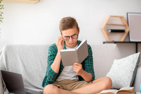 Evde gözlüklü bir öğrenci kitap okuyor. — Stok fotoğraf