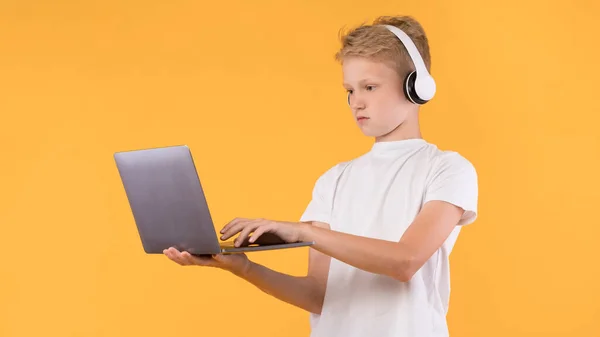 Skupiony nastolatek stojący z laptopem i maszynopisem — Zdjęcie stockowe