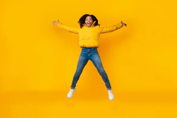 Joyful African Girl Doing Spread Eagle Jump Over Yellow Background — Stock Photo, Image