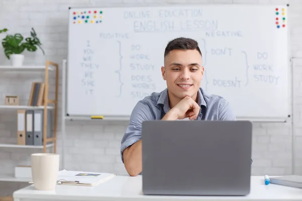 Tutor bewertet das Wissen der Schüler. Junger Mann schaut im Klassenzimmer auf Laptop — Stockfoto