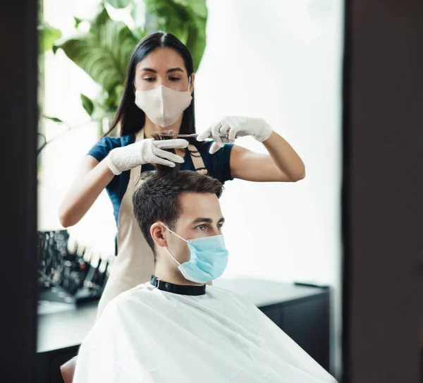 Cabeleireiro jovem em máscara protetora corte de cabelo do cliente masculino — Fotografia de Stock
