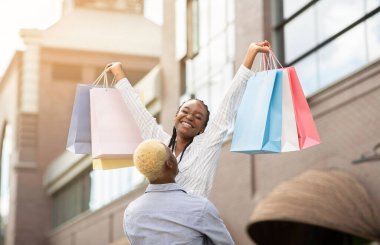 Birlikte yürürken mutlu anlar. Afrikalı Amerikalı milenyum çocuğu çantalı kadını aldı.