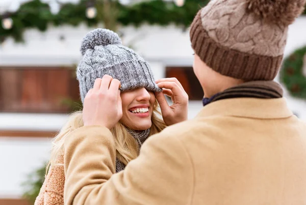 Romantiskt par som har roligt utomhus på vintern, man leker med flickvänner hatt — Stockfoto