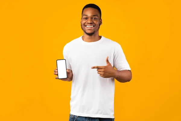 Positivo negro chico mostrando teléfono vacío pantalla en amarillo fondo — Foto de Stock