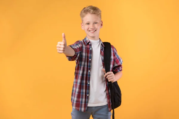 Glimlachende tiener jongen tonen duim omhoog in studio — Stockfoto
