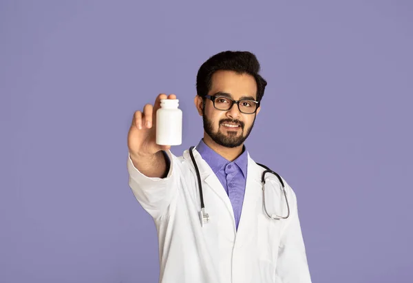 Feliz médico indio mostrando frasco de tabletas con maqueta para el diseño sobre fondo lila — Foto de Stock