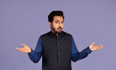 Kim bilir? Kafası karışmış Hintli adam mor arka planda omuz silkiyor.