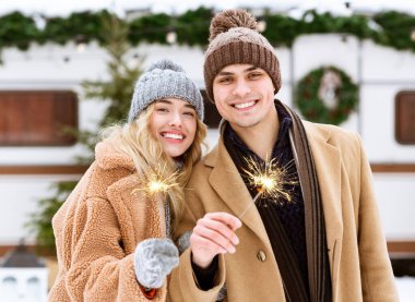 Bengal ışıklarıyla kışın dışarıda poz veren mutlu romantik çift