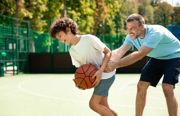 Sportive dad teaching his son how to play basketball — Stock Photo, Image