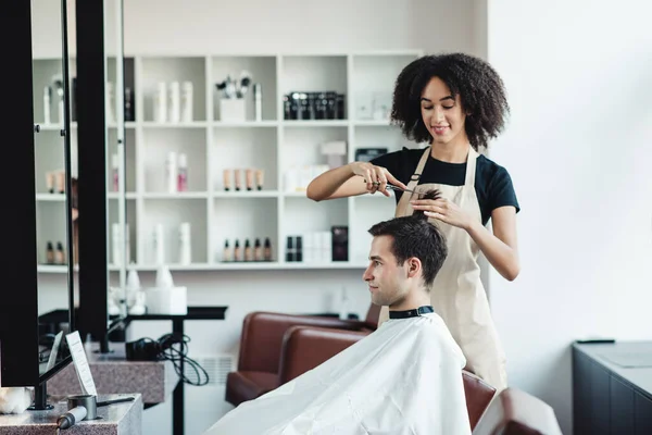 Kobieta czarny fryzjer cięcia włosy młody mężczyzna klient — Zdjęcie stockowe