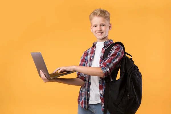 Счастливый парень с ноутбуком в руках и в желтой студии — стоковое фото