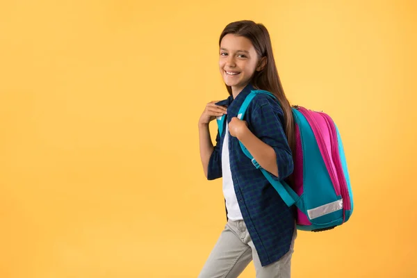 Glimlachend schoolmeisje poseren met schooltas op studio achtergrond — Stockfoto