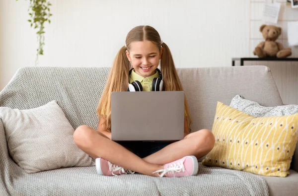 女孩坐在沙发上，用手提电脑 — 图库照片