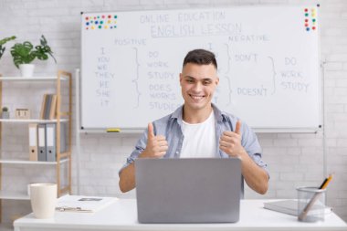 Mükemmel çalışma sonucu. Gülümseyen genç öğretmen, online derste öğrencileri övüyor.