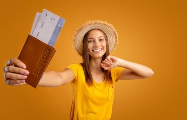 Pasaportunu uçuş biletleriyle gösteren neşeli bir kız.
