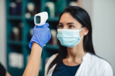 İşçi elinde ultra-ötesi ısı tarayıcısı olan kadın müşteri başı