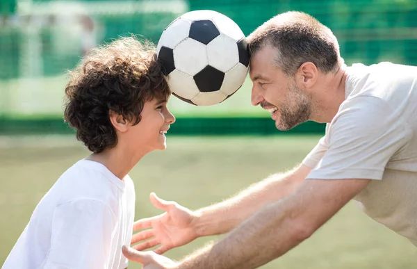 Man holding ball between two heads with little boy — Stock Photo, Image