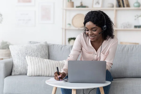 Imparare a distanza. Positiva donna nera che studia con computer portatile e auricolare a casa — Foto Stock