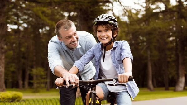 Boy learning to ride bicycle with his happy dad — Stock Photo, Image
