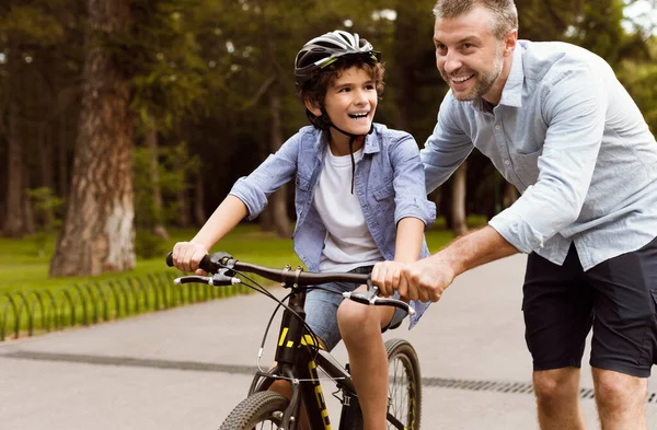 Boy learning to ride a bicycle with his adult father — Stock Photo, Image