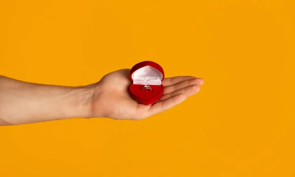 Caja de espera hombre irreconocible con anillo de compromiso sobre fondo naranja, primer plano —  Fotos de Stock