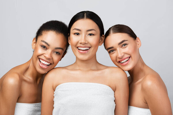 Three Young Women Laughing Posing Wrapped In Towels, Gray Background