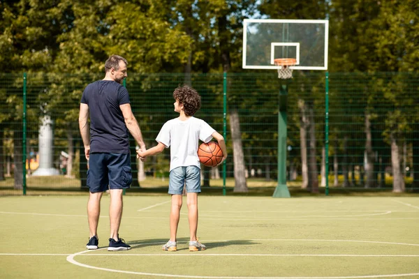 Άνθρωπος ποζάρουν με μικρό αγόρι στο γήπεδο του μπάσκετ πίσω όψη — Φωτογραφία Αρχείου