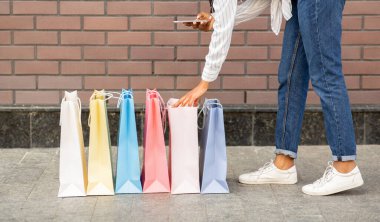 Modern giyim blogu için video. Afrikalı Amerikalı kız çantalardaki alışverişlerin fotoğrafını çekiyor.