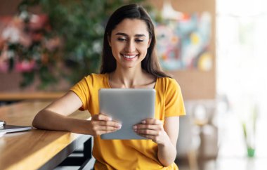 Kafede dijital tablet kullanan mutlu Arap kız