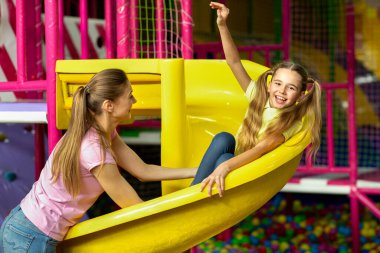 Genç anne ve kızı oyun parkında eğleniyorlar.