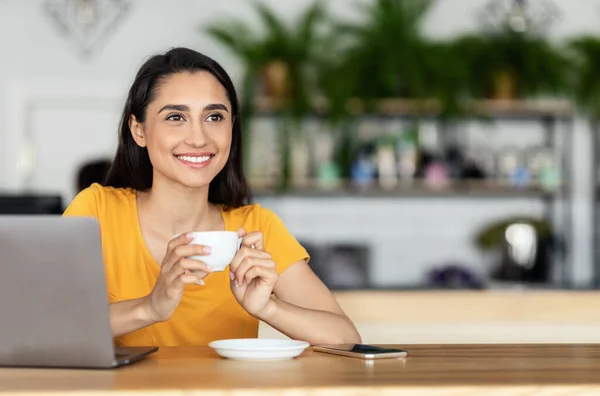 Šťastná mladá žena pije kávu v kavárně, pomocí notebooku — Stock fotografie