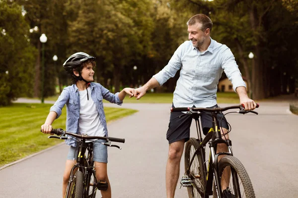 Man giving fist bump to son riding bicycles — Stock Photo, Image