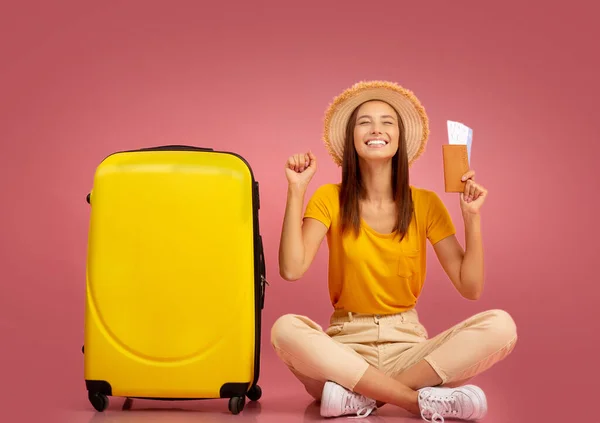 Verheugd meisje met paspoort zittend in koffer — Stockfoto