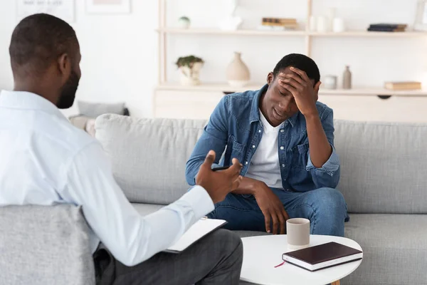 Psychotherapie concept. Depressieve zwarte man in gesprek met psycholoog tijdens individuele therapie — Stockfoto