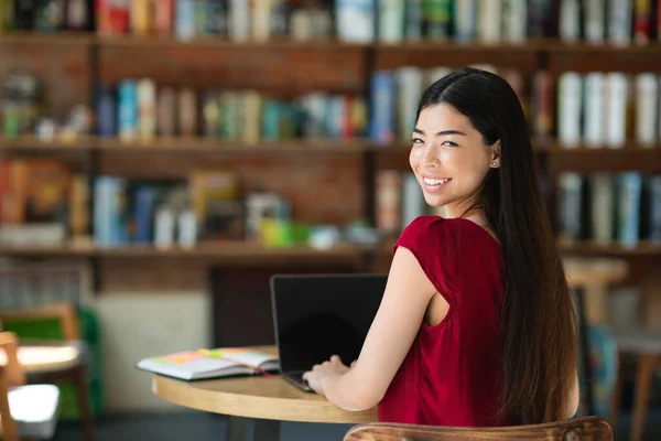 《偏远就业》。亚洲女孩在咖啡店使用带有黑屏的笔记本电脑 — 图库照片