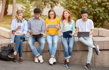 Çeşitli Öğrenciler Laptop ve Tablet Bilgisayarlarını Dışarıda Oturarak Öğreniyor