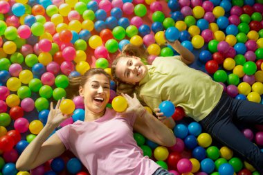 Eğlenceli aile zamanları. Anne ve kızının kapalı lunaparktaki top havuzunda yatışının genel görüntüsü.
