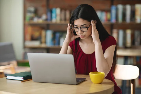 Concentrado asiática nerd estudiante chica en gafas estudiar en línea con el ordenador portátil en café — Foto de Stock