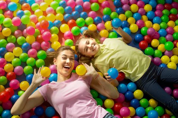 Divertidos momentos familiares. Vista aérea de la madre con su hija acostada en el estanque de bolas en el parque de atracciones interior — Foto de Stock