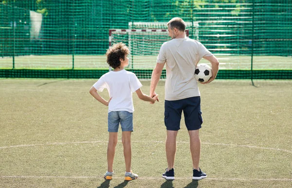 Man posing with little boy on football pitch back view — Stock Photo, Image