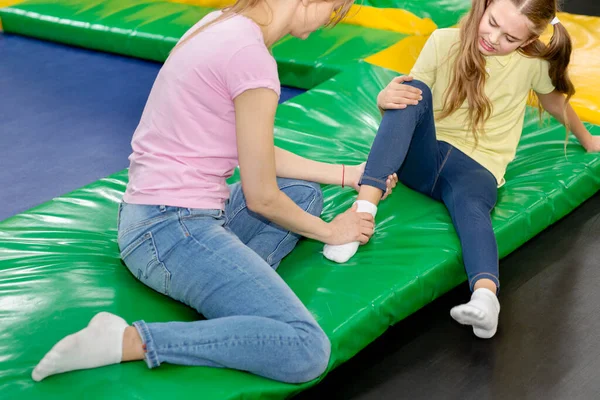 Trambolinde, kapalı alanda atladıktan sonra bileğindeki ağrıdan endişelenen anne ve kızı.