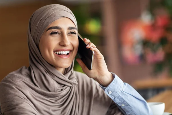 Rire fille musulmane parlant au téléphone tout en se reposant au café — Photo