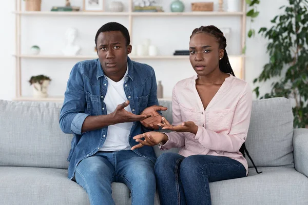 Frustrated Black Couple Sitting On Couch At Therapy Session, Looking With Misunderstanding