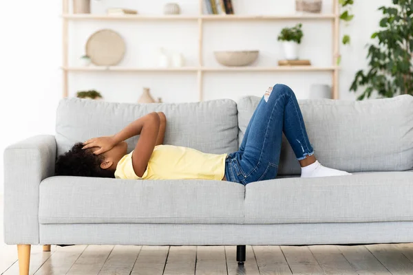 Απογοητευμένο μαύρο κορίτσι που κλαίει καλύπτοντας το πρόσωπο ξαπλωμένο στον καναπέ — Φωτογραφία Αρχείου