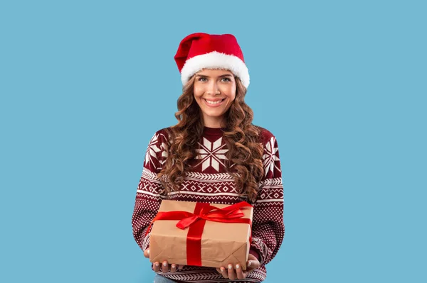 Compras de invierno. Hermosa chica milenaria en traje de Navidad sosteniendo caja de regalo sobre fondo azul — Foto de Stock