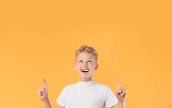 Sonriente chico apuntando con el dedo hacia arriba en el espacio de copia — Foto de Stock