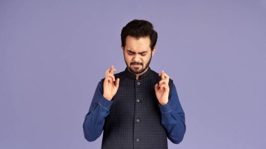 Dilek tutuyorum. Batıl inançlı Hintli bir adamın portresi menekşe arka planda parmaklarını çapraz tutuyor.