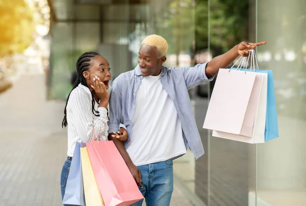 Geschokt Afrikaan amerikaanse man wijst op etalage, meisje met open mond — Stockfoto