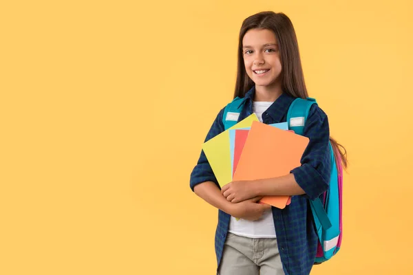 Usmívající se dívka drží učebnice na pozadí studia — Stock fotografie